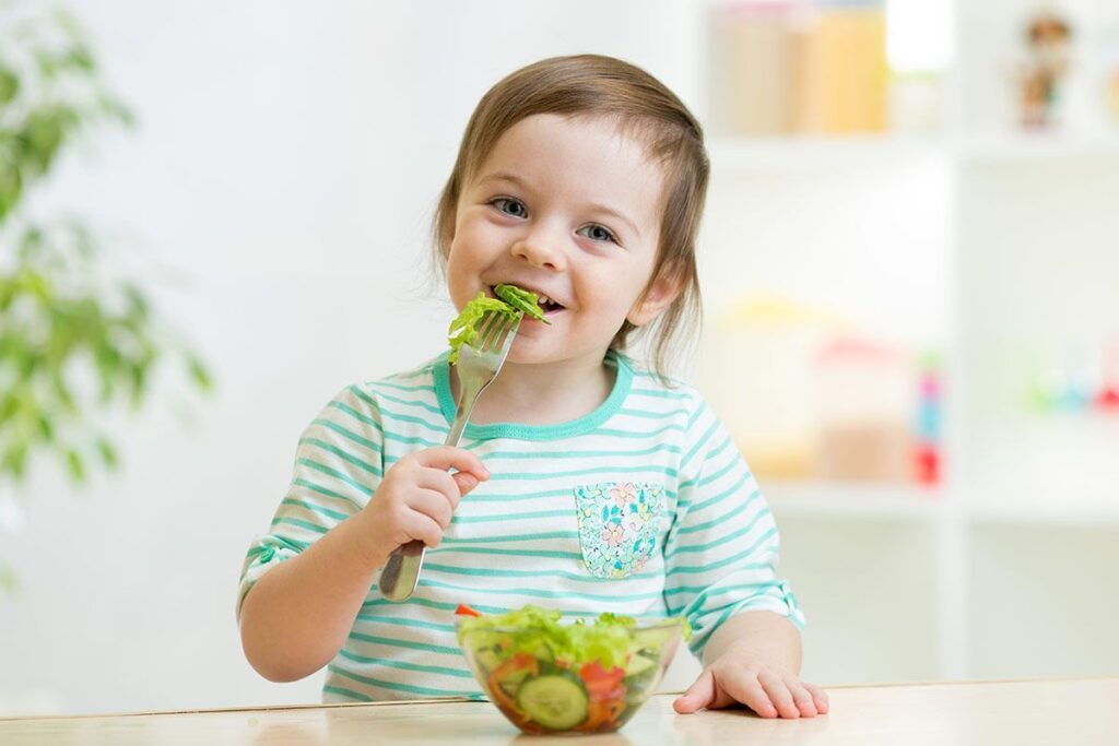 Niño pequeño comiendo ensalada de vegetales
